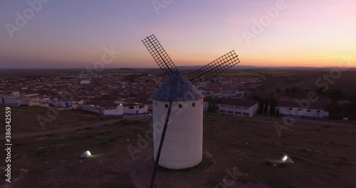 Aerial view Beautiful sunset over white cylindrical towers and pointed roofs of old Spanish windmills on background with Campo de Criptana, Spain
