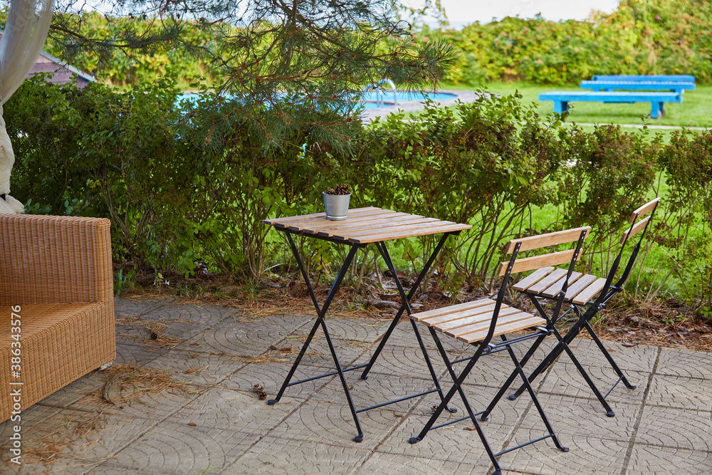 Obraz premium A bucket of pine cones on an empty garden table and two chairs