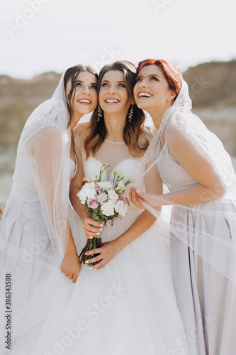 Fotografía Pretty bride with friends posing under a wedding veil