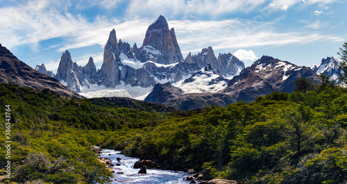 Forest crossed by the glacial river in El Chalten National Park, Argentina, Patagonia with Mount Fitz Roy and Cerro Torre in the background