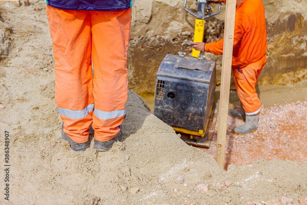 Worker compacting foundation using vibration plate compactor Worker compacting foundation using vibration plate compactor