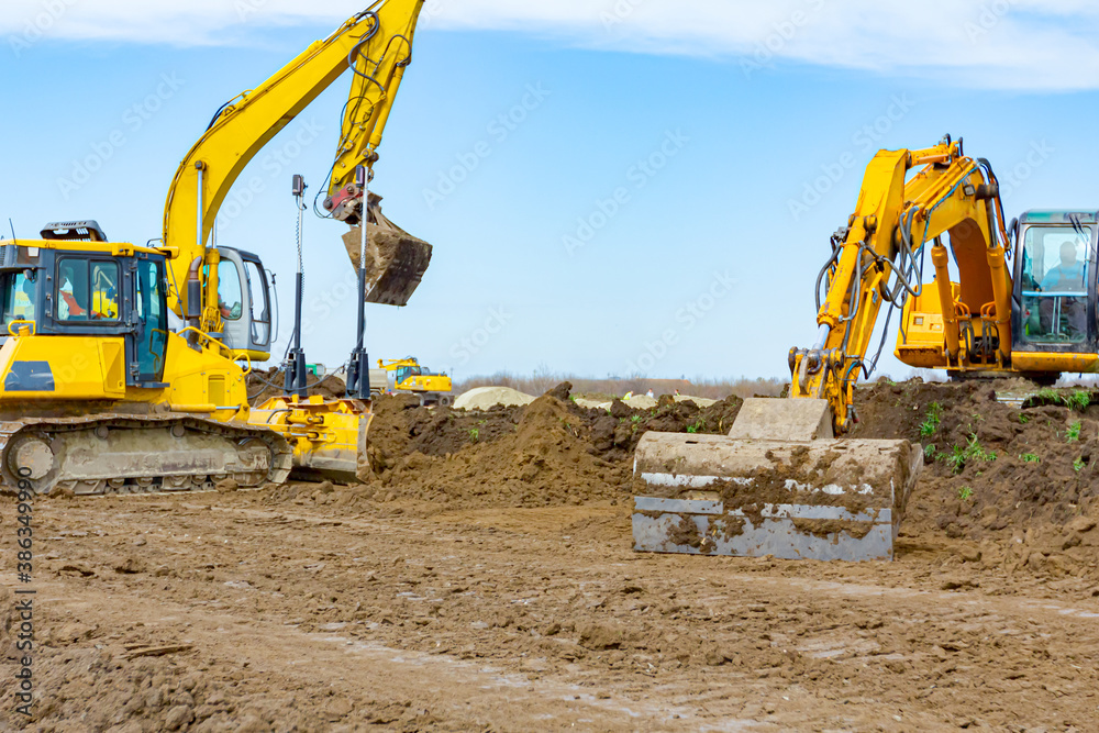 Two excavators and earthmover are leveling ground construction site