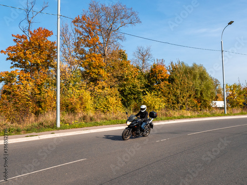Motorcyclist in motion. Woman biker on a black motorcycle in traffic on a rural autumn road © sablinstanislav