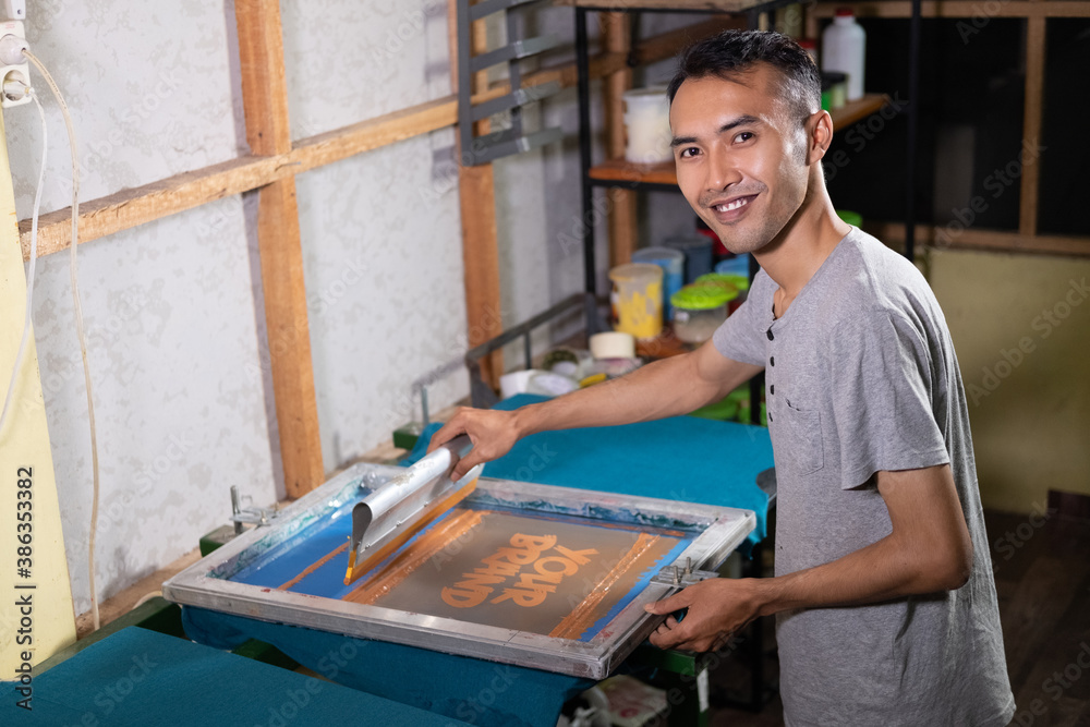 Silk screen printing and wooden frame using the screen printing squeegee to print  T-shirts at the workshop Photos | Adobe Stock