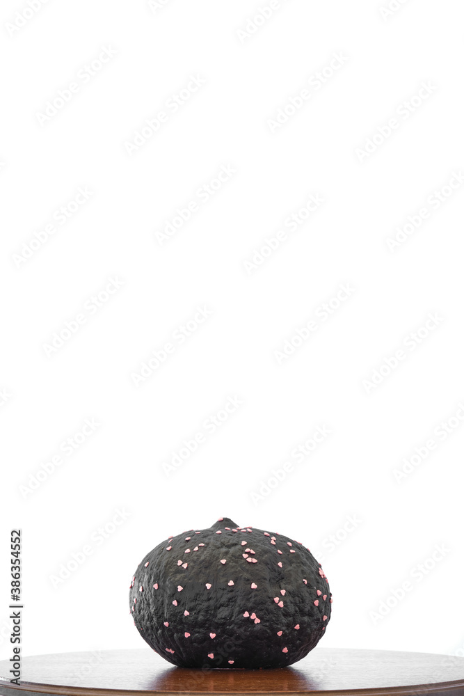 black coloured pumpkin with glitter on wooden stool in front of a white backdrop black coloured pumpkin with glitter on wooden stool in front of a white backdrop