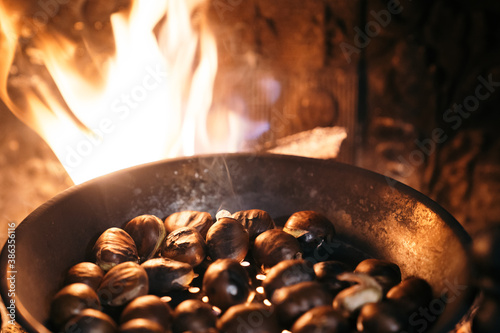 Roasting chestnuts with fire and wood in a fireplace at home. Celebrating the 