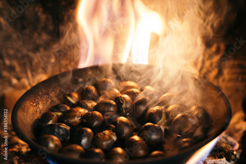 Chestnuts roasted in the chimney and smoking. Roasting chestnuts with a fire in the house. Celebrating the 