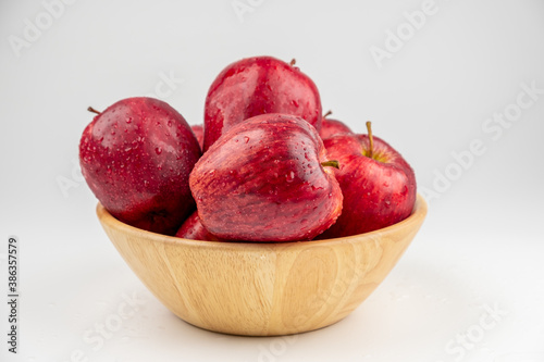 Pile of red apple in wooden bowl with clear water drop on 
shell surface texture pattern isolated, white background