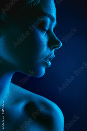 Passion. Portrait of female fashion model in neon light on dark studio background. Beautiful caucasian woman with trendy make-up and well-kept skin. Vivid style, beauty concept. Close up. Copyspace