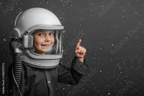 A small child imagines himself to be an astronaut in an astronaut's helmet. © vovan