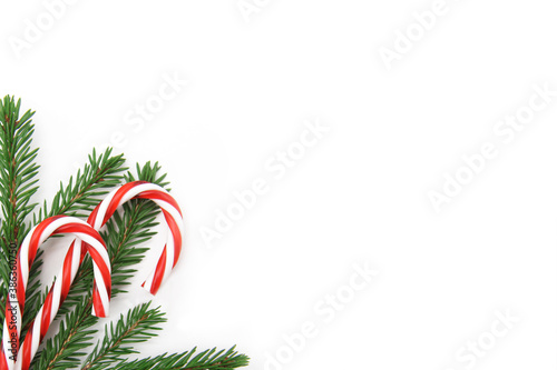 Christmas card concept - Christmas gifts on a white background. Red and white candy canes, green Christmas tree branches, flat lying with copy space