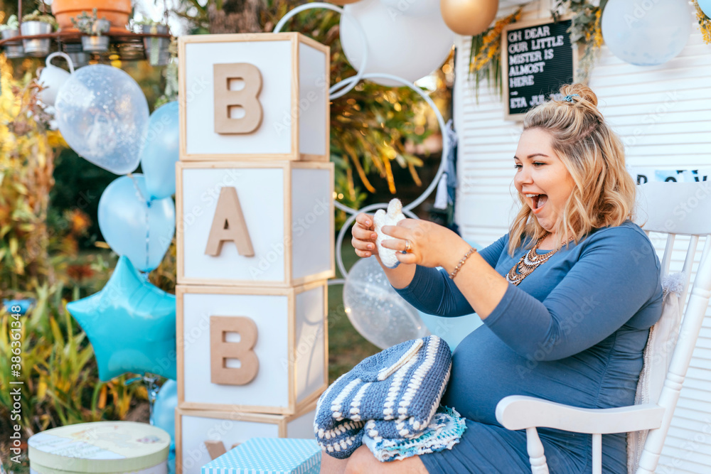 Pregnant woman sits on a Baby shower party setup and looking at the