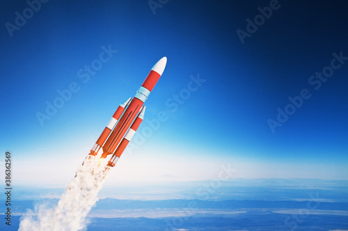 Fototapeta Naklejka Na Ścianę i Meble -  Flying red rocket on blue sky background.