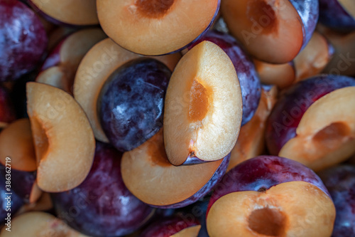 Food background of cutted halfs of blue plums. Top view with selective focus