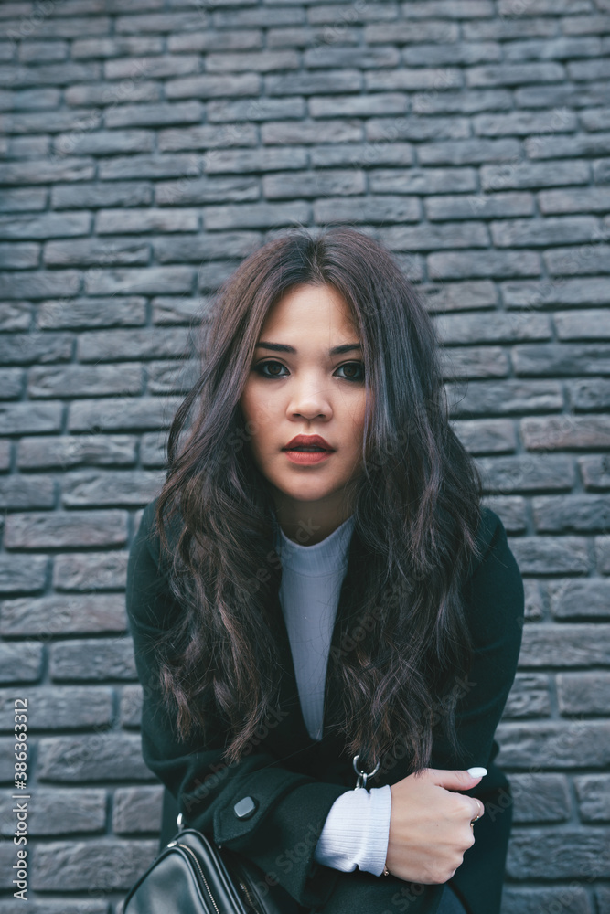 Portrait of young adult asian female in black coat outdoors, selective focus Portrait of young adult asian female in black coat outdoors, selective focus