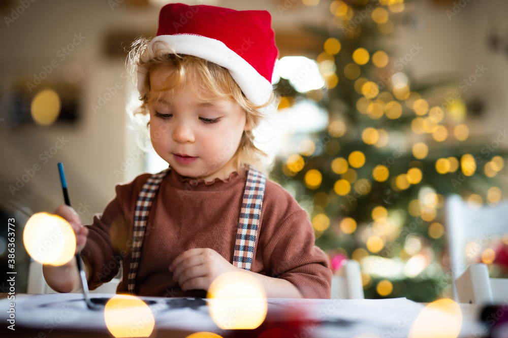 Portrait of small girl indoors at home at Christmas, painting pictures. Portrait of small girl indoors at home at Christmas, painting pictures.