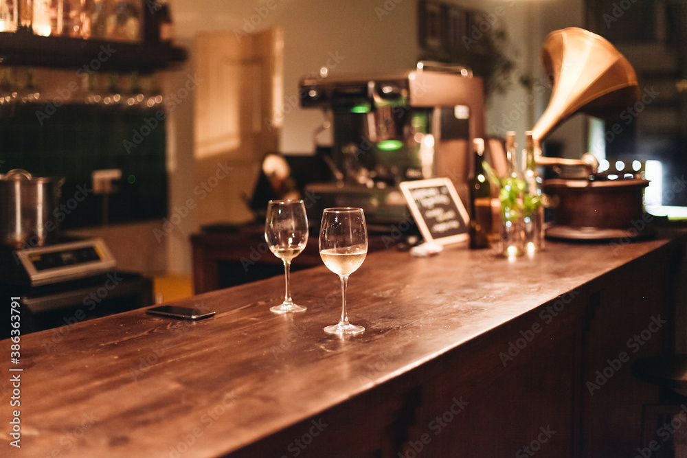 Two glasses of white wine in a dark cozy bar. Wine served on a wooden table