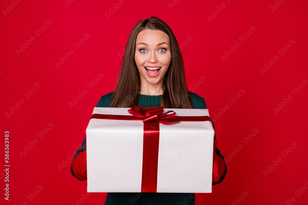 Photo of astonished girl hold big x-mas gift box wear green pullover isolated over bright shine color background Photo of astonished girl hold big x-mas gift box wear green pullover isolated over bright shine color background