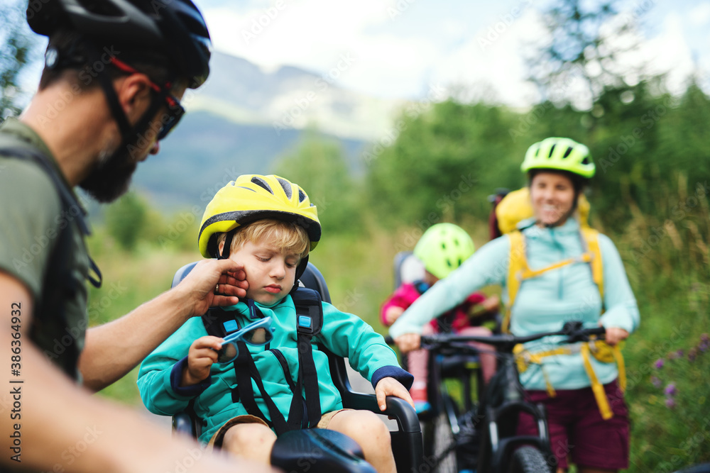 Family with tired small children cycling outdoors in summer nature. Family with tired small children cycling outdoors in summer nature.