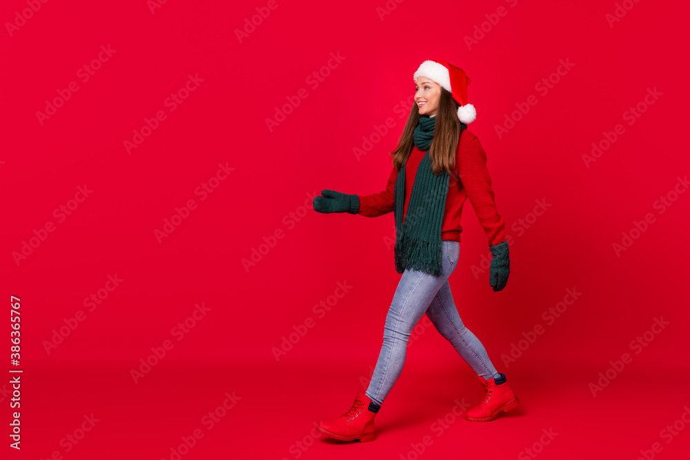 Full length body size profile side view of her she nice attractive cheerful girl wearing festal cap walking copy space isolated over bright vivid shine vibrant red color background Full length body size profile side view of her she nice attractive cheerful girl wearing festal cap walking copy space isolated over bright vivid shine vibrant red color background