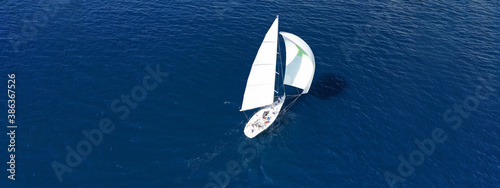 Aerial drone ultra wide panoramic photo of beautiful sailboat with white sails cruising deep blue sea near Mediterranean destination port
