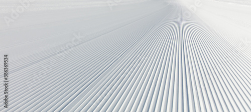 Close-up straight line rows of freshly prepared groomed ski slope piste.