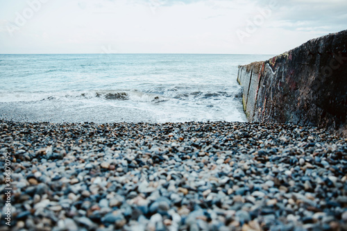 Seascape. Blue and gray pebbles on the beach. White sea waves. Skyline. Nature multicolored background. photo