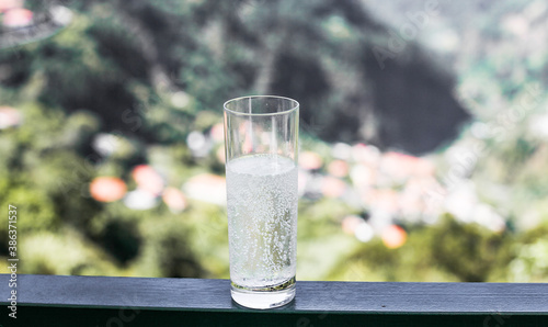 A glass of sparkling water, green mountains on the background