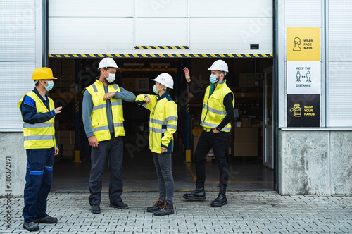 Group of workers with face mask greeting in front of warehouse, coronavirus concept.