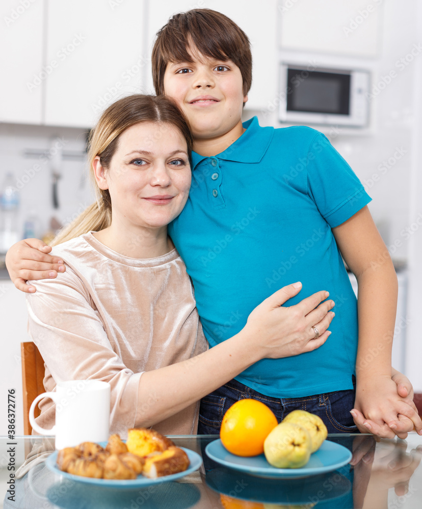 Portrait of happy family of mother and son eating at home kitchen