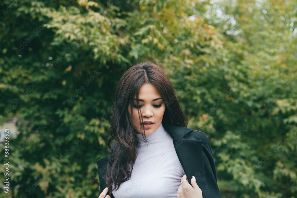 Beautiful portrait of young adult asian female in dark coat and white sweater outdoors Beautiful portrait of young adult asian female in dark coat and white sweater outdoors