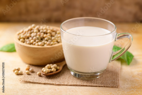 Soy milk in the glass and soy beans on wooden background