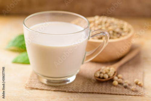 Soy milk in the glass and soy beans on wooden background