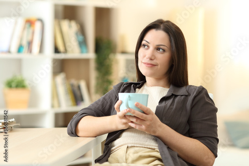 Woman thinking looking at side drinking coffee
