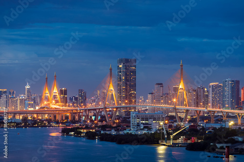 Large suspension bridge over Chao Phraya river at twilight, with city in background