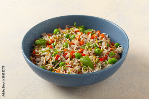 Trendy lunch with rice and vegetables. Served in a blue bowl, on a bright painted background. Front view.