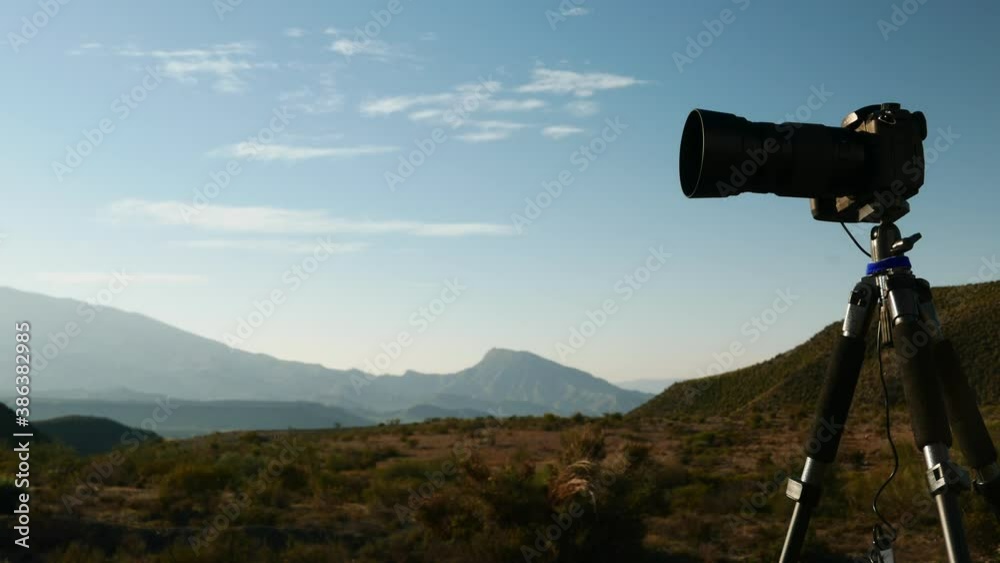 Professional camera on tripod taking travel picture in Tabernas desert, Andalusia Spain. Clouds moving over hills landscape. Time lapse Professional camera on tripod taking travel picture in Tabernas desert, Andalusia Spain. Clouds moving over hills landscape. Time lapse