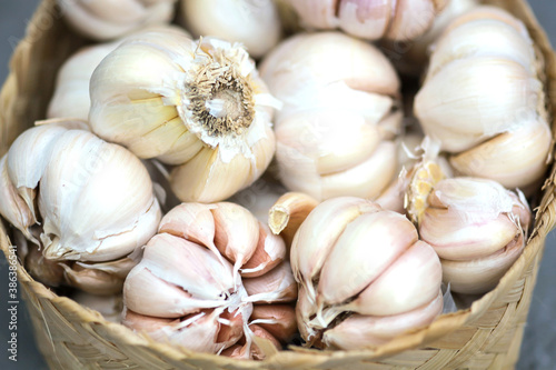 Blurry and close up photo of garlic in a wicker baskets on gray background