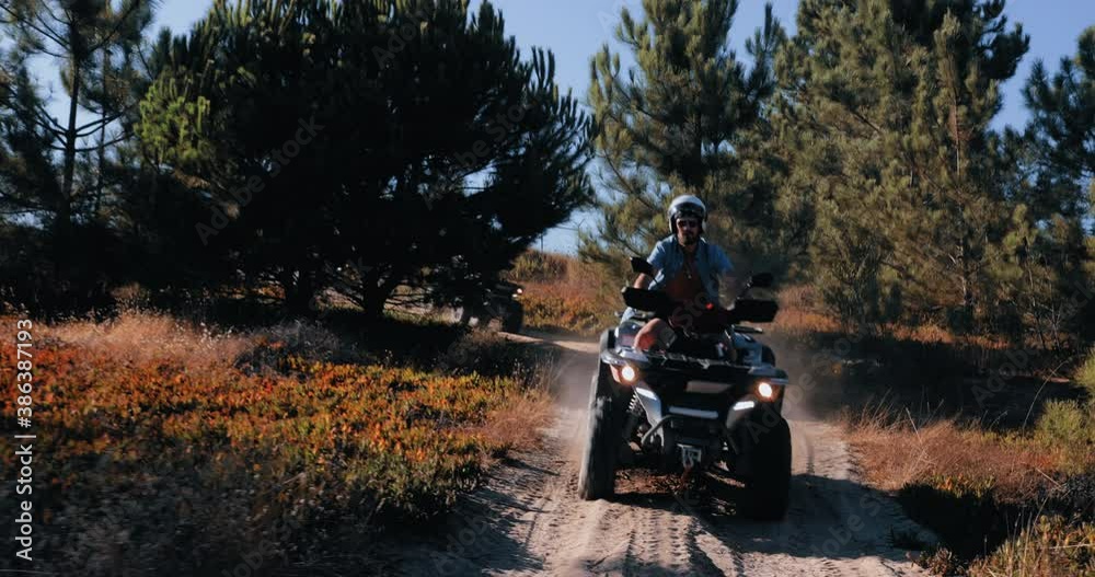 Friends with helmets riding quad bikes together in the forest Friends with helmets riding quad bikes together in the forest
