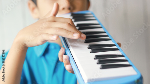 Boy playing blue melodeon musical instrument  melodica blow organ  pianica or melodion on blurry white background.
