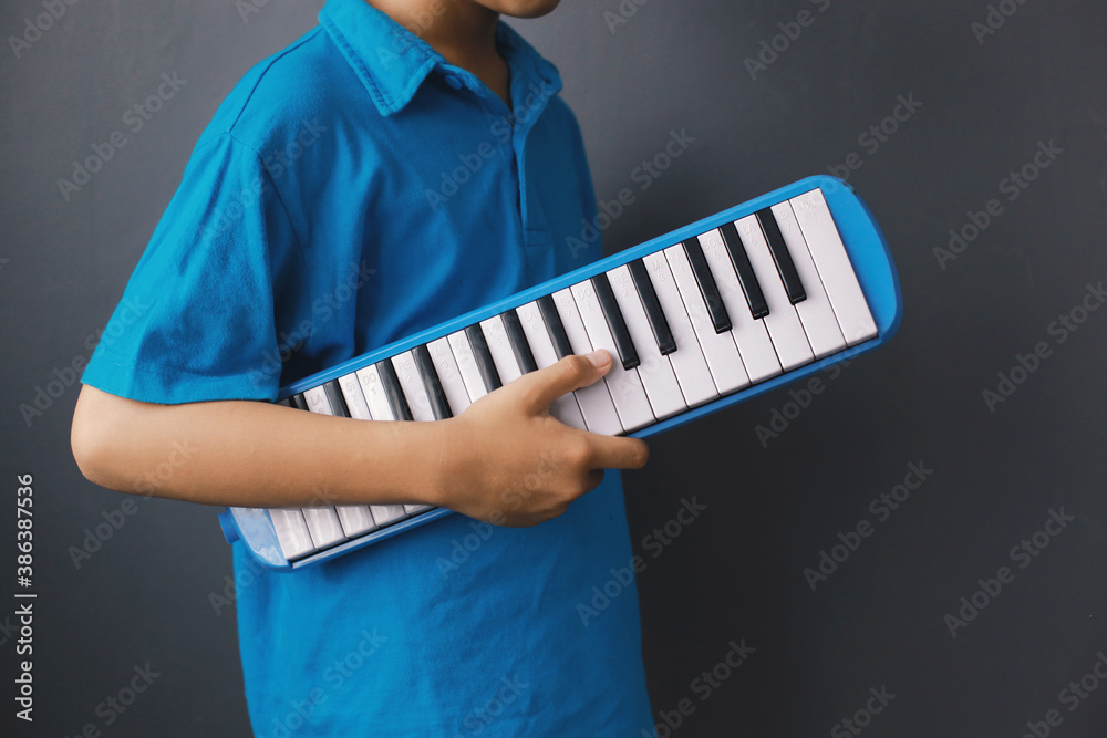 Boy playing blue melodeon musical instrument, melodica blow organ