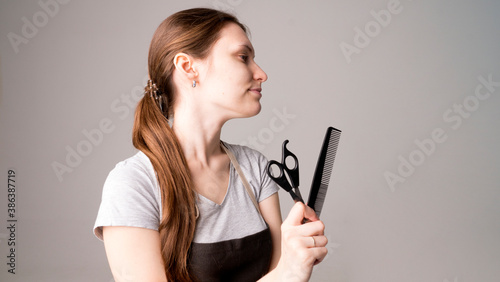 Young beautiful female hairdresser holding hair clipper