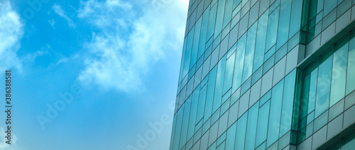 Modern office building with reflection of blue sky and clouds on its windows