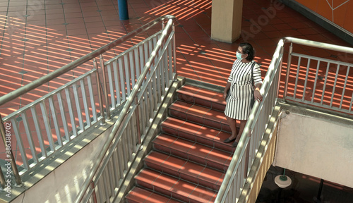 Woman wearing face mask standing on the staircase