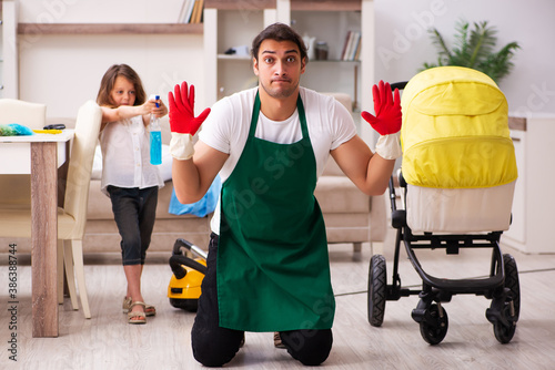 Young male contractor cleaning the house with his small daughter
