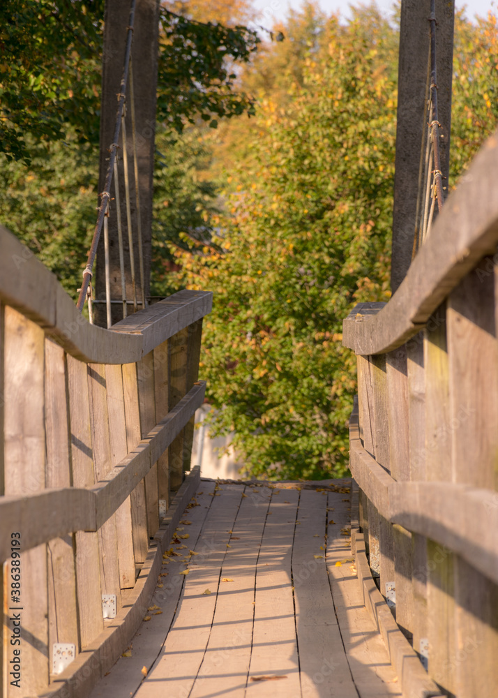 wooden bridge over the river, trees and shrubs in the background wooden bridge over the river, trees and shrubs in the background