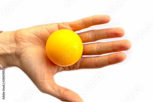 Yellow plastic ball lies on a female hand on a white background.