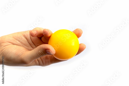 Female hand fingers holding yellow plastic ball isolated on white background.
