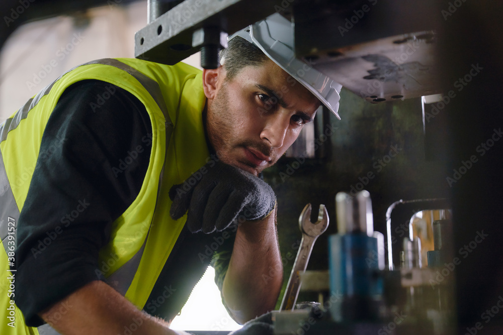 Engineer portrait though from machine foreground with wrench in manufacturer Engineer portrait though from machine foreground with wrench in manufacturer