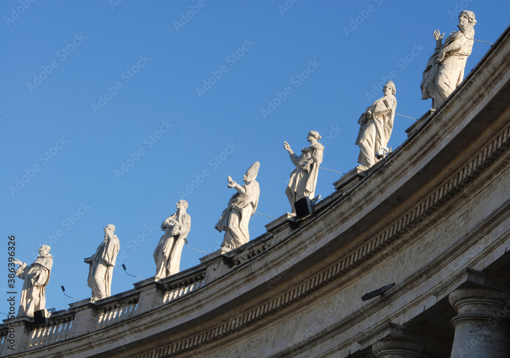 Obraz premium The famous colonnade of St. Peter's Square with statues in the Vatican state that is formed by large columns of travertine in a circular shape.